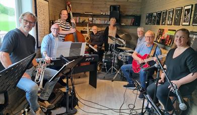 Jensens jazzband består av fra venstre Trond Vetterstad(trompet), Børre Jensen(piano), Robert Opsahl(bass), Nils Petter Hobbelstad(sax), Ann Karin Nilsen(vokal), Egil Fritzøe(trommer), Halvard Foss(gitar) og Heidi Medalen Westbye(vokal).